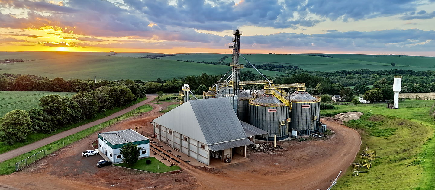 Vista aérea da unidade da Agropohl ao entardecer, com os silos, o barracão e o escritório